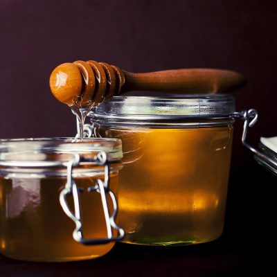 Two jars of honey with a honey dipper.